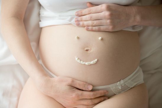 Smiley Face Drawn On Pregnant Belly With Face Cream