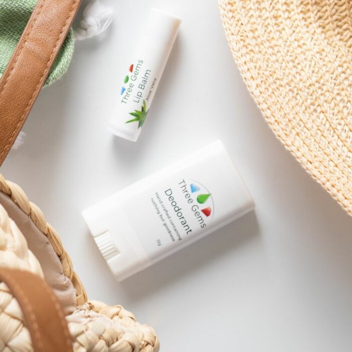Travel size natural deodorant with lip balm and parts of a bag and hat