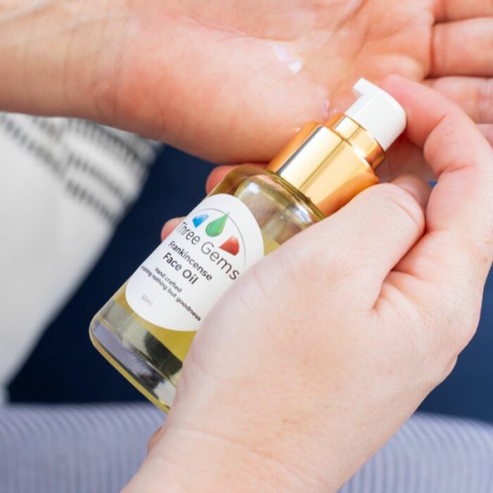 Three Gems organic face oil being put on a ladies hand for use