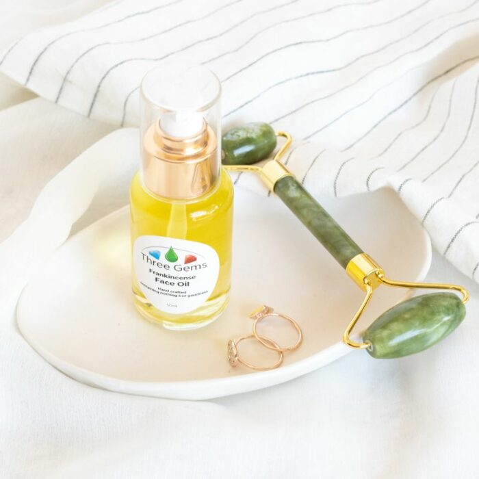 Organic face oil and a jade roller on a dish with rings