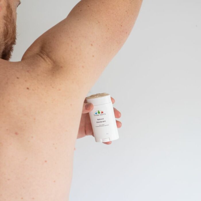 A man applying the Three Gems Natural Deodorant to his underarm
