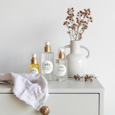 Three Gems Cleanser, Toner, And Frankincense Face Oil On A Table With A Dried Flower Arrangement